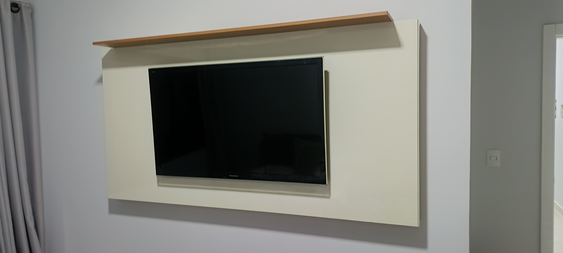 Painel de TV branco com prateleira de madeira instalado
